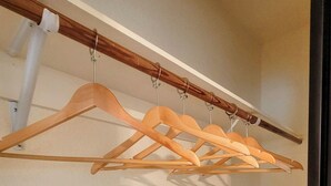 Een kast met houten kleerhangers en witte planken.