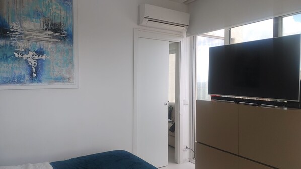 Una habitación con cama, televisión de pantalla plana, aire acondicionado y un cuadro en la pared.