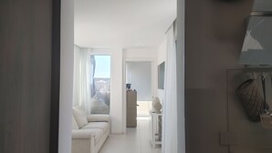 A modern hotel room with a sofa, a small table, and a view of the cityscape through large windows. - PENTHOUSE ON CATANIA HARBOR AND VOLCANO VIEW A FEW STEPS FROM CATHEDRAL (Catania)