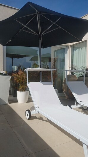 Un espace extérieur moderne, aménagé avec deux fauteuils confortables et un grand parasol.