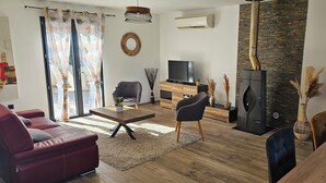 Een moderne woonkamer met een bank, een salontafel, een televisie en een open haard.