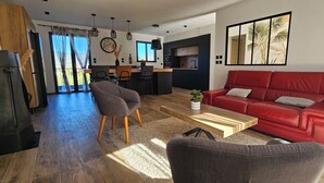 Een moderne woonkamer met een rode bank, een grijze fauteuil en een houten salontafel.