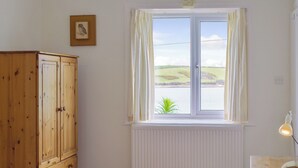 Une chambre avec une armoire en bois, un radiateur, une fenêtre avec des rideaux et une lampe de chevet.