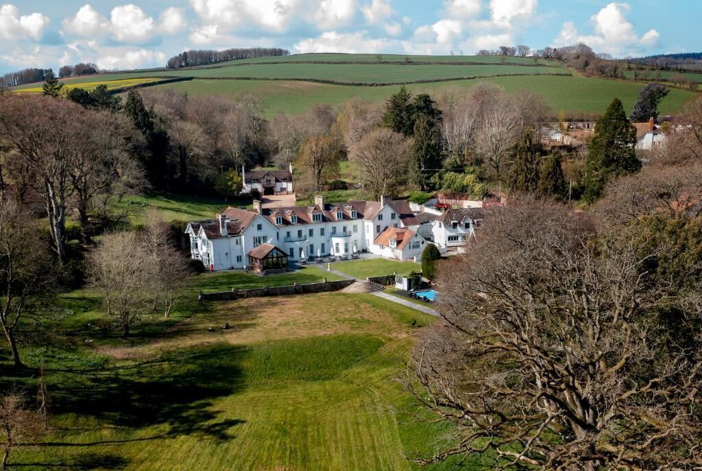 A large estate with multiple buildings, a well-maintained lawn, and surrounding fields.