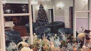 Una sala moderna con un espejo grande, un árbol de Navidad y un arreglo floral.