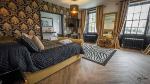 Un dormitorio con una cama grande, un sofá, un televisor y vistas al exterior.