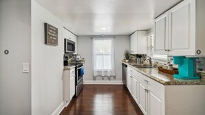 A narrow kitchen with white cabinets, a microwave, and a coffee maker. - Charming Seminole Heights Stay with Free Parking (Tampa)