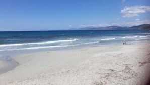 Una platja amb aigua turquesa cristal·lina, sorra daurada i muntanyes al lluny.