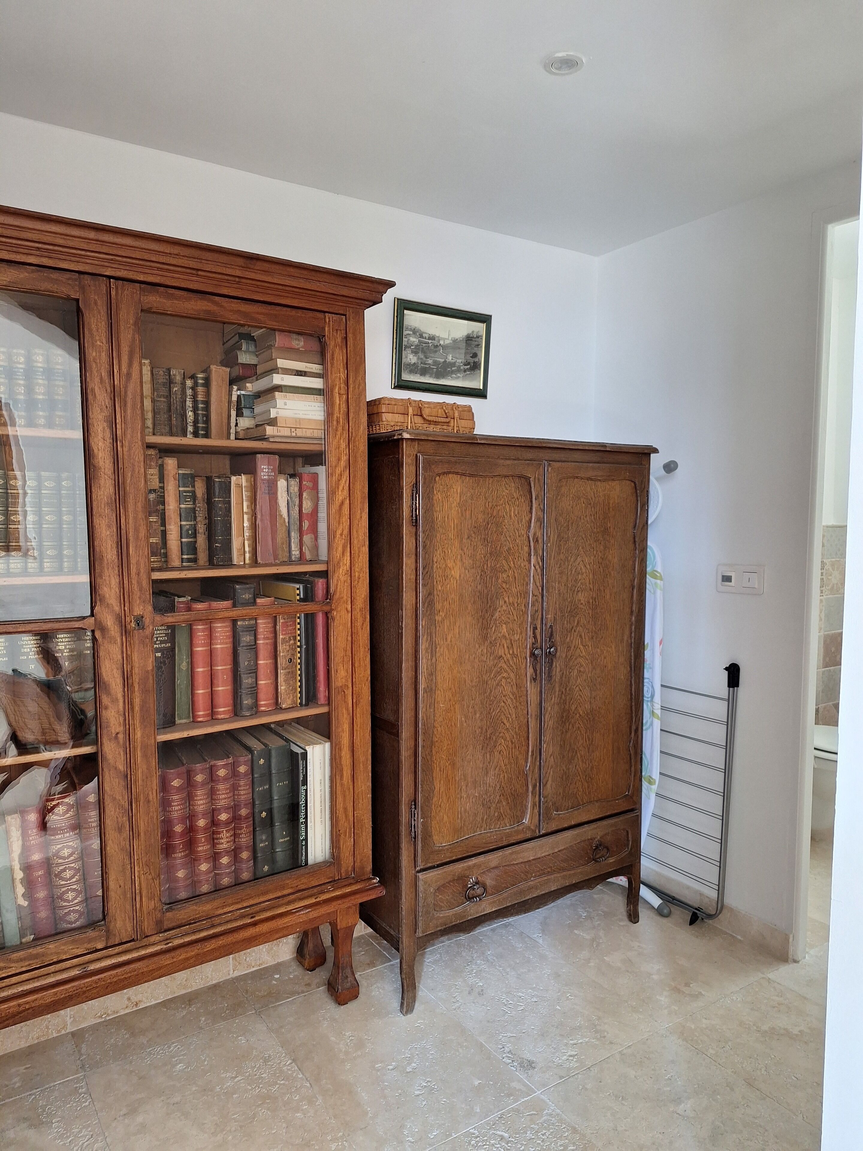 A room with a wooden bookcase filled with books, a wooden cabinet, and a radiator.