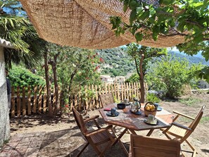 An outdoor dining area with a wooden table and chairs, surrounded by a wooden fence and trees.