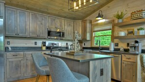 Een moderne keuken met houten kastjes, roestvrijstalen apparatuur en een centraal eiland met barstoelen.