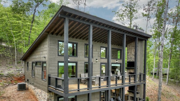 Een meerlaags chalet met een balkon, buitenzitplaatsen en een hottub.