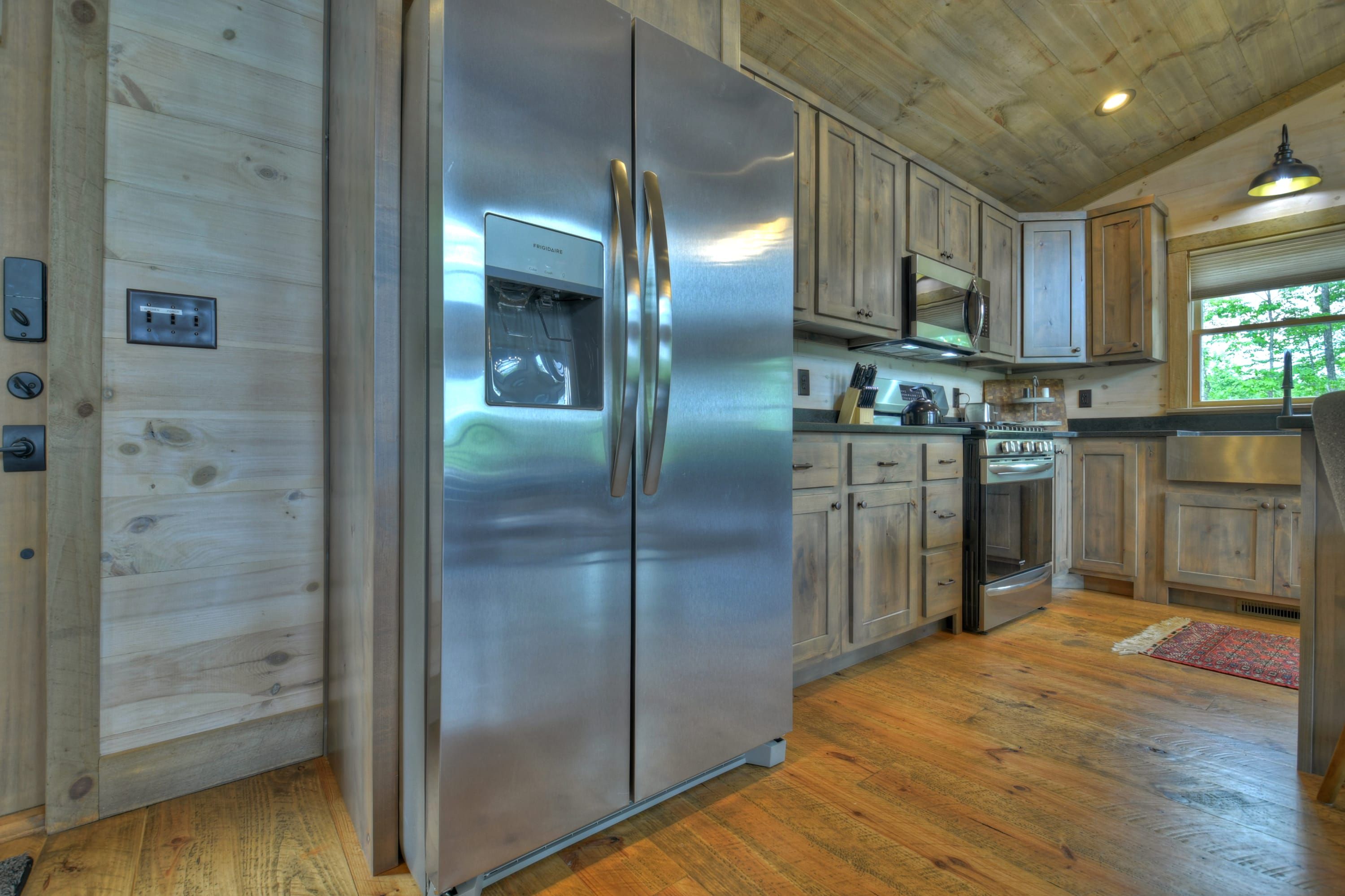 Una cocina moderna con refrigerador de acero inoxidable, armarios de madera y microondas integrado.