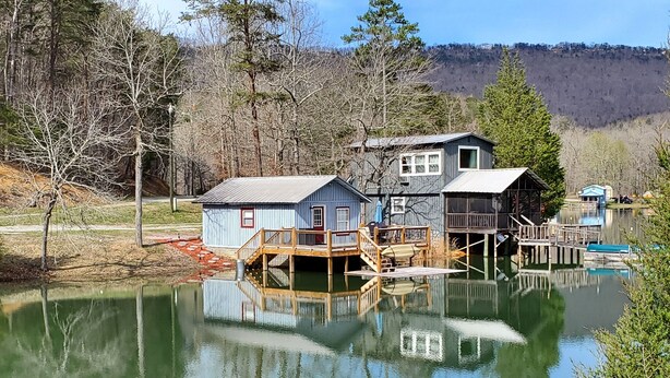 Conjunto de cabañas junto al lago con acceso a muelle, rodeado de árboles y una vista despejada del lago.