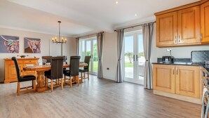 Uma cozinha espaçosa com armários de madeira e uma sala de jantar com mesa e cadeiras.