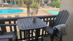 A balcony with a pool table, chairs, and a small table with a mug. - Sea Esta Getaway - Largo Mar (Panama City Beach)