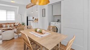 Una cocina moderna con armarios blancos, una mesa de comedor de madera y una lámpara colgante.