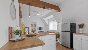 Una cocina moderna con encimera de madera, armarios blancos y un refrigerador de acero inoxidable.