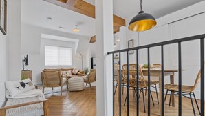 Un amplio salón con piso de madera, una mesa de comedor con sillas y un gran ventanal que proporciona luz natural.