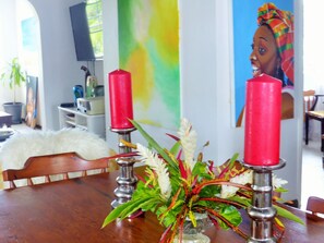 A dining area with a wooden table, two red candles, and a floral centerpiece. - Cozy apartment in a tropical setting with art studio (Micoud)