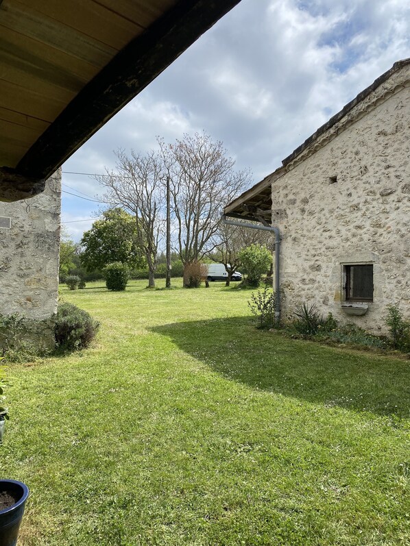 Un edificio de piedra rústico con un porche cubierto y un patio con césped.