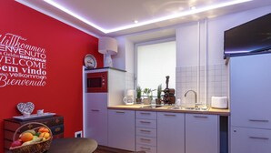 Eine moderne Küche mit roter Akzentwand, weißen Schränken und einem Essbereich mit Tisch und Bank.