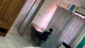 Un dormitorio con cama, escritorio, silla, armario y baño con cortina de ducha.