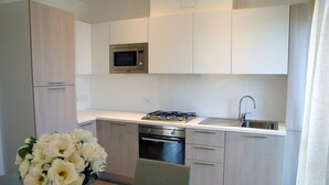 Een moderne keuken met een magnetron, gasfornuis, oven en spoelbak.