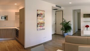 Een modern appartement met keuken, woonkamer en een televisie op een standaard.