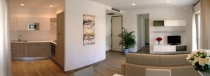 Un appartement moderne comprenant une cuisine, un espace de vie et un téléviseur posé sur un meuble.