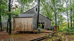 A wooden cabin with a deck, surrounded by trees. - Welcome to Wellfleet! Classically Modern, Woodsy and Serene. (Wellfleet)