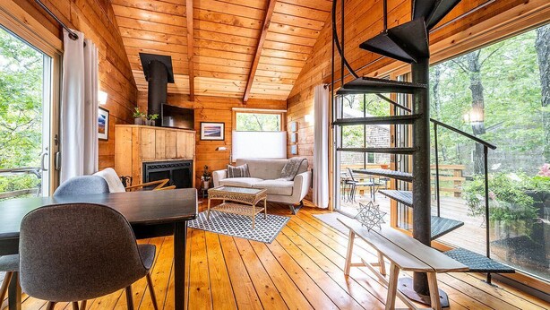 A cozy cabin interior with a wooden floor, a sofa, a dining table, and a fireplace. - Welcome to Wellfleet! Classically Modern, Woodsy and Serene. (Wellfleet)