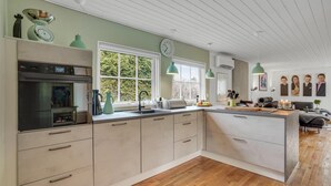 A modern kitchen with a built-in oven, a sink, and a window overlooking greenery. - Beautiful home in Højby with WiFi (Højby)
