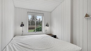 A bedroom with a large bed, two wall-mounted lamps, a window with a view of trees, and a small nightstand. - Beautiful home in Højby with WiFi (Højby)