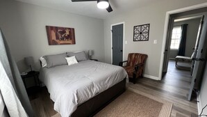Un dormitorio con cama, ventilador de techo, puerta y una silla.