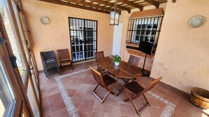 Une terrasse avec une table et des chaises en bois, une plante en pot et des carreaux décoratifs.