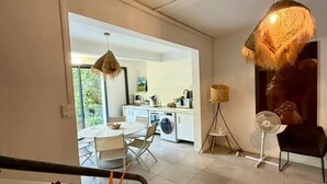 Een open woon- en eetruimte met een keuken op de achtergrond, een eettafel met stoelen, en een grote plant.