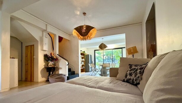 Een ruime slaapkamer met een groot bed, een zithoek met een tafel en stoelen, en een trap naar een hoger niveau.
