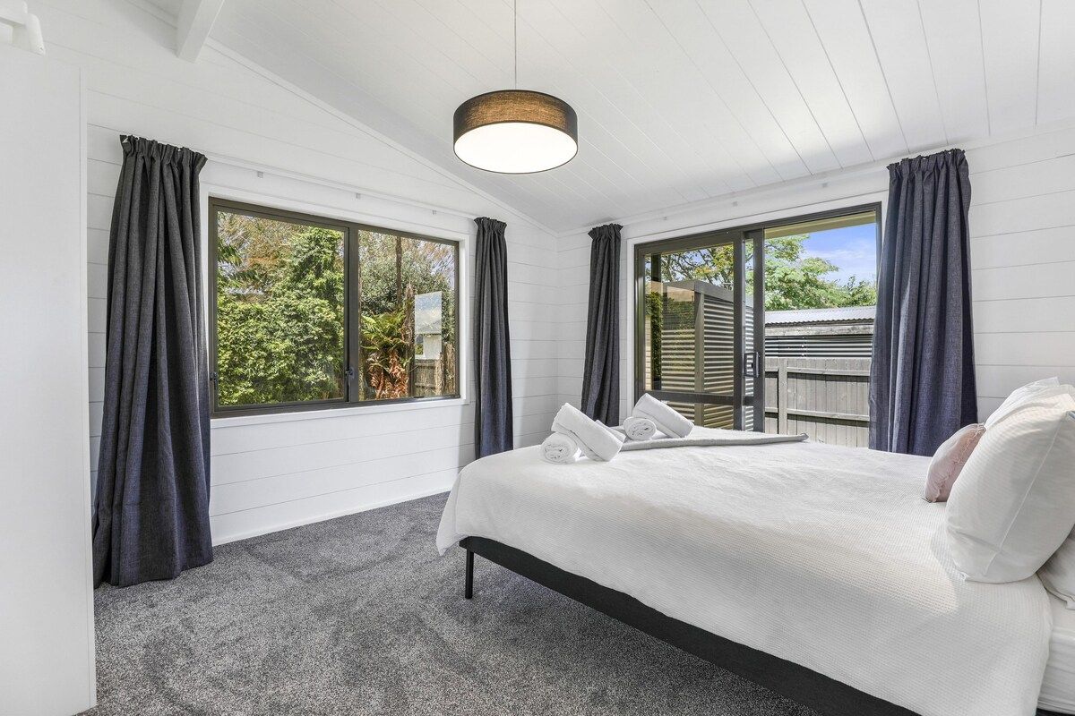 A bedroom with a bed, curtains, and a view of greenery outside.