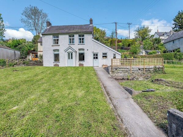 A two-story house with a stone wall and a wooden fence in front. - 2 bedroom accommodation in Knighton (Knighton)