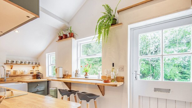 A modern kitchen with wooden countertops, a built-in stove, and a large window offering a view of greenery.