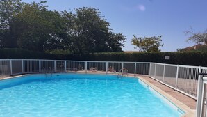Ein rechteckiger Swimmingpool mit weißem Metallzaun darum herum.