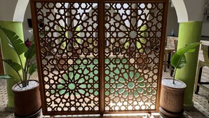 A view of a room with a decorative screen, potted plants, and a tiled floor. - Riad La Petite Rose (Marrakech)