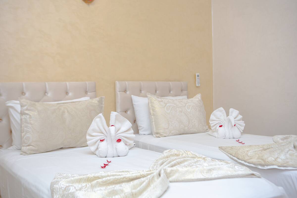 A hotel room with a large bed, white bedding, and decorative towels shaped like swans.