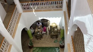 A multi-level courtyard with a central green area, seating arrangements, and decorative elements. - Riad La Petite Rose (Marrakech)