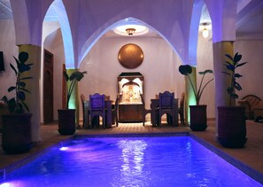 Un área de piscina con un espacio de descanso y una fuente decorativa.