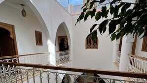 A courtyard with white walls, multiple arches, and a decorative metal railing. - Riad La Petite Rose (Marrakech)