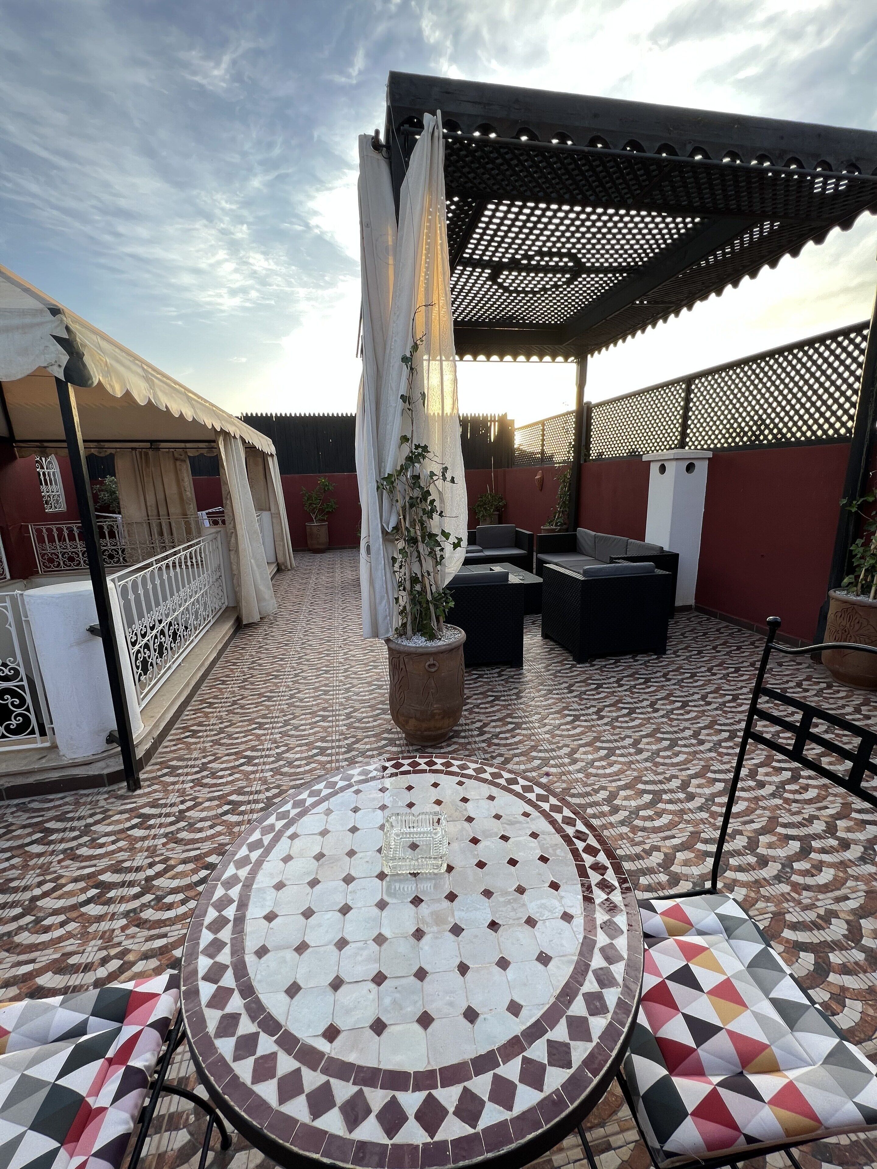 Un espacio al aire libre cubierto con piso de baldosas, una mesa y sillas.