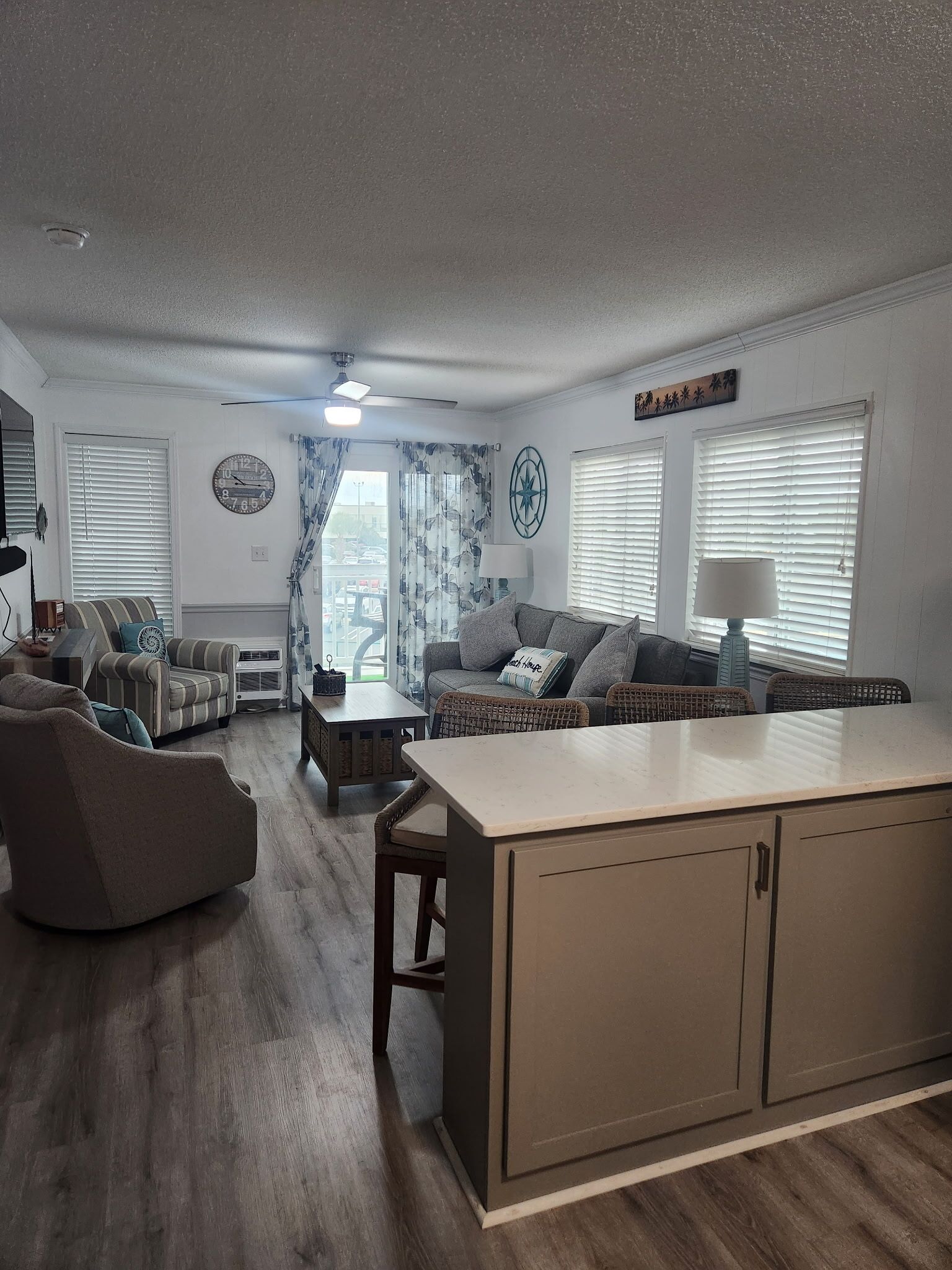 A living room with a sofa, armchairs, a coffee table, and a kitchen island.
