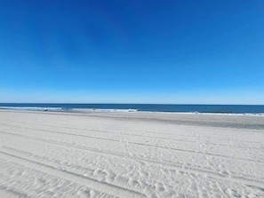 Une vaste plage de sable fin, avec des vagues douces et un ciel bleu dégagé.